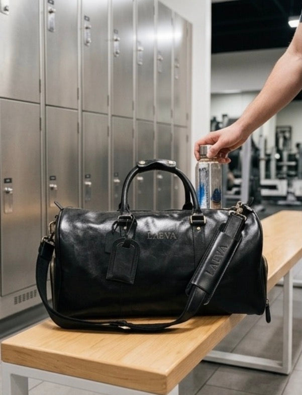 Black duffel bag on a bench with a person holding a bottle in a locker room setting.